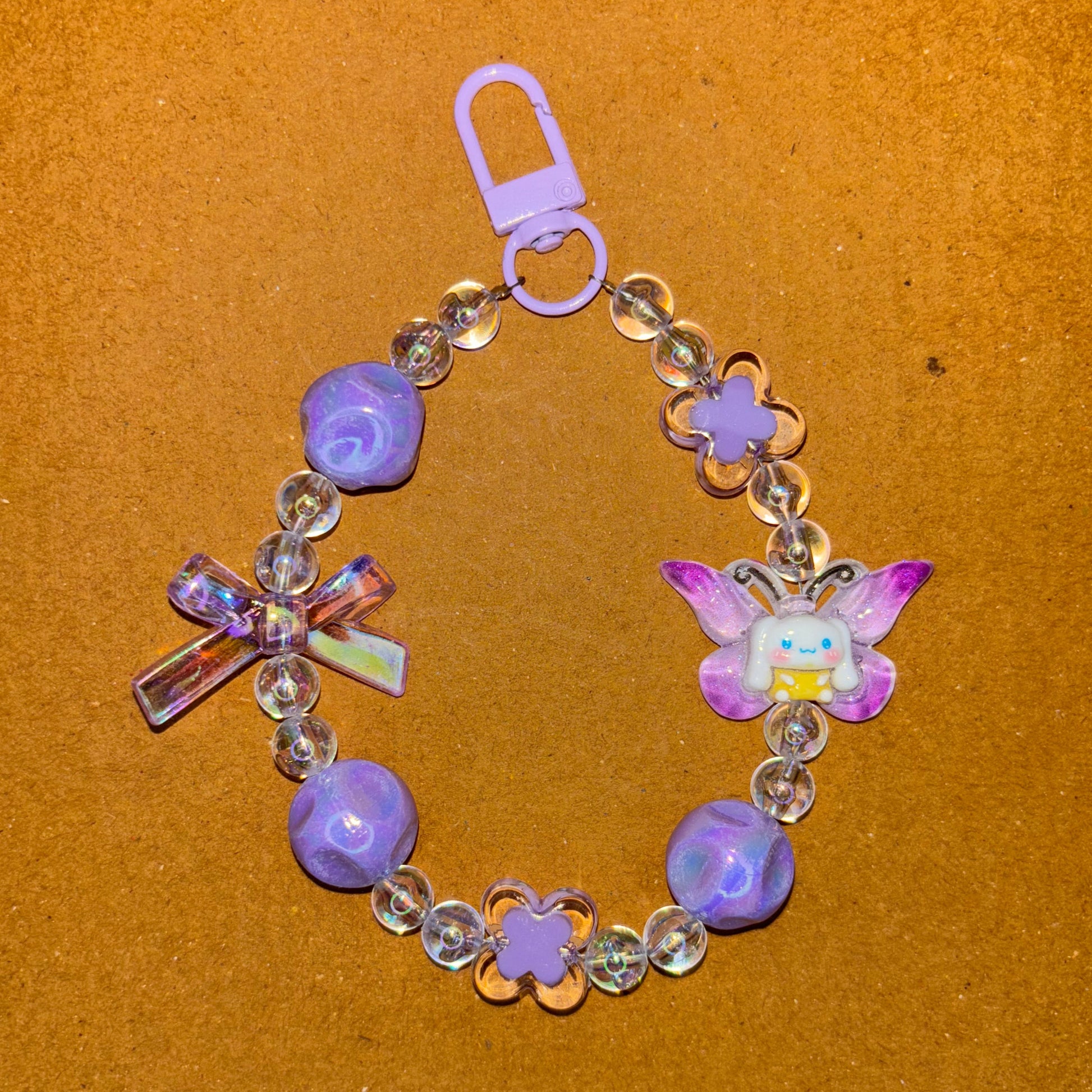 Children's bracelet with purple beads and a butterfly charm on a brown background
