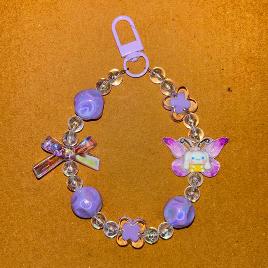Children's bracelet with purple beads and a butterfly charm on a brown background