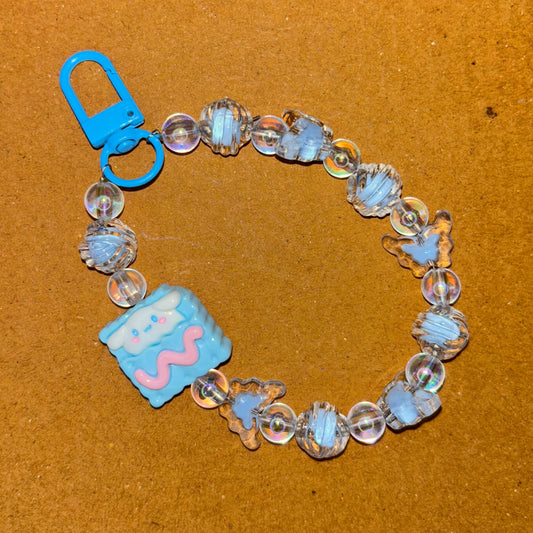 Bracelet with blue and clear beads and a blue charm on a brown background
