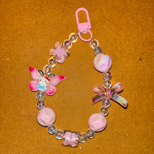 Pink beaded bracelet with butterfly charms on a brown background