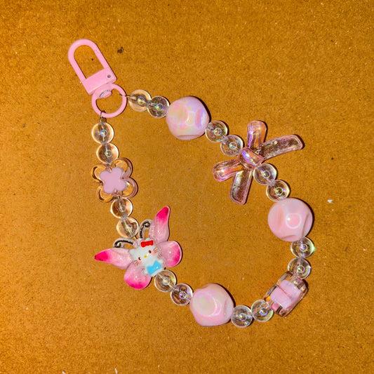 Decorative keychain with pink flowers and beads on a brown background