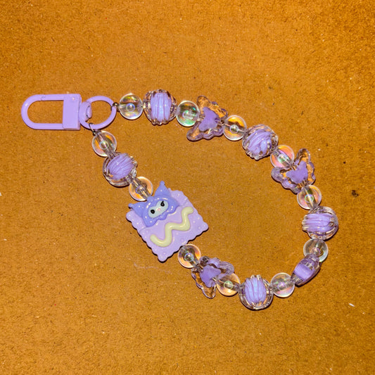 Beaded bracelet with a purple charm on a brown background