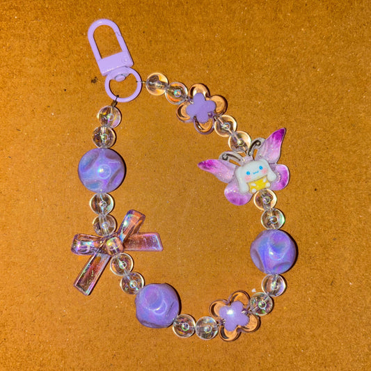 Decorative bracelet with purple beads and charms on a brown background
