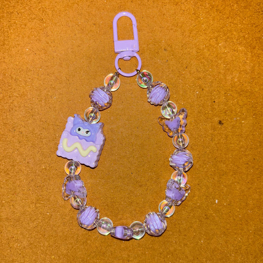 Beaded bracelet with a purple charm on a brown surface