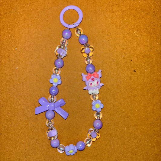 Children's bracelet with purple beads and decorative charms on a brown background