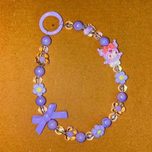 Bracelet with purple beads and floral designs on a brown background