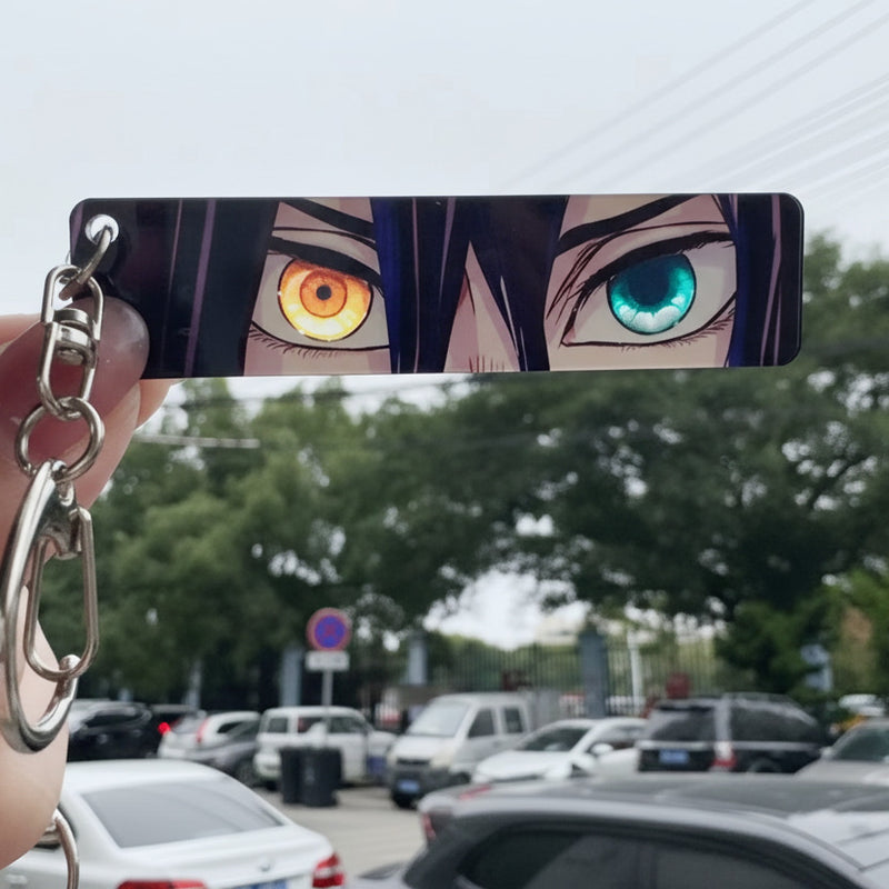 Anime character keychain with multicolored eyes held by a hand in an outdoor setting.
