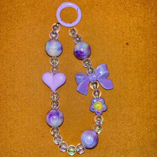 Beaded bracelet with purple flowers and hearts on a brown background